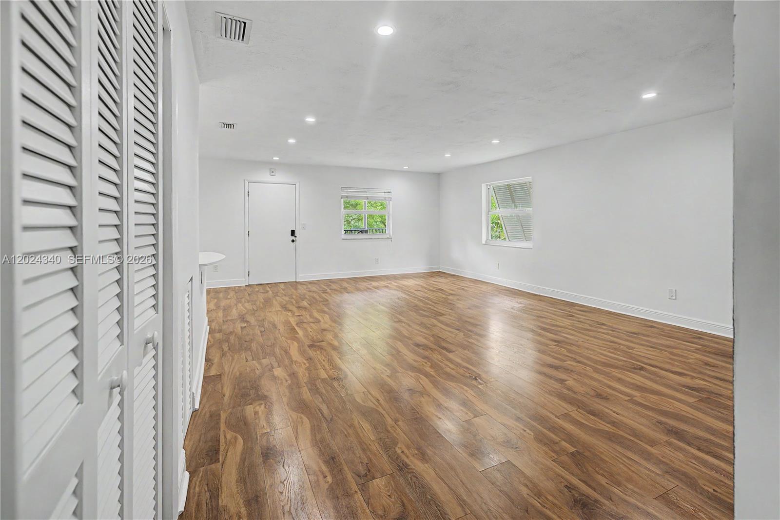 An empty room features white walls, recessed lighting, and wood-look flooring — 6815 Edgewater Dr # 201, Coral Gables FL 33133, CORAL GABLES, FL