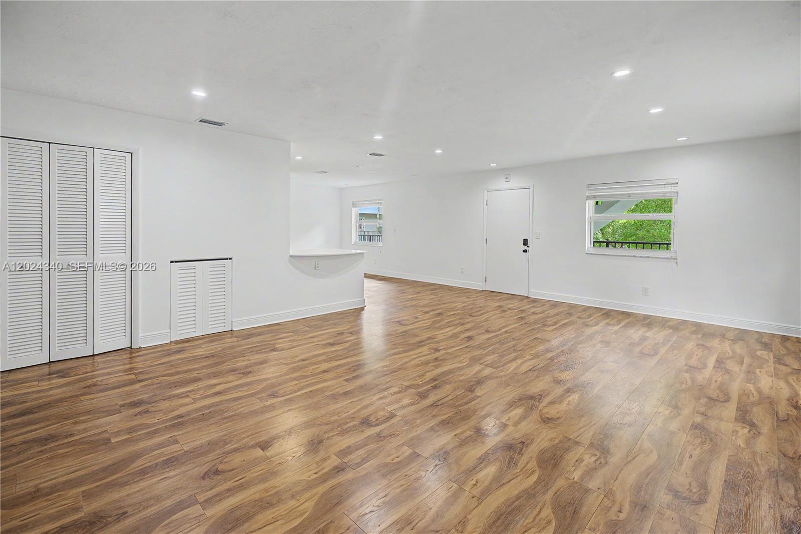 An empty room features white walls, wood-look flooring, recessed lighting, and a small breakfast bar — 6815 Edgewater Dr # 201, Coral Gables FL 33133, CORAL GABLES, FL