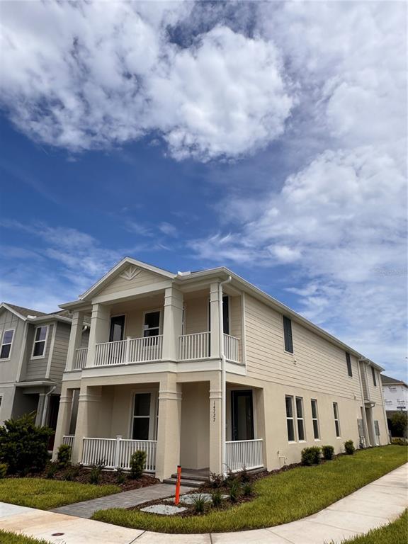 A two-story beige house features a front porch, a second-story balcony, and white railings — 14727 FIELD DAISY DRIVE, WINTER GARDEN, FL