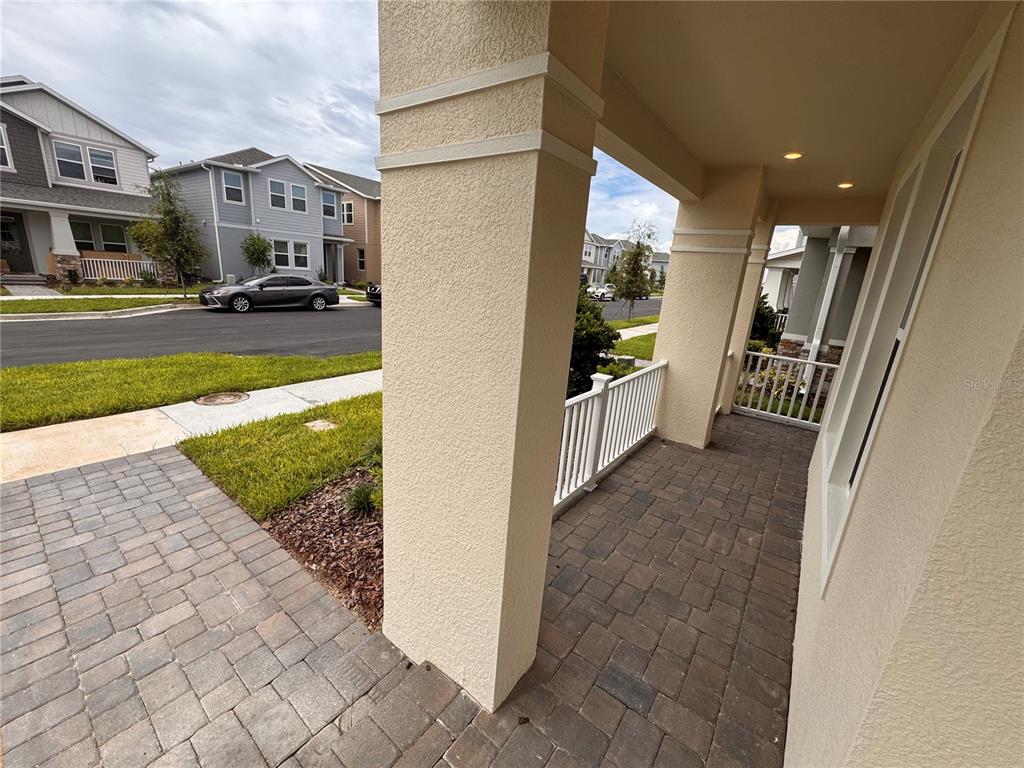 A covered front porch with stone pavers, a white railing, and a large support pillar — 14727 FIELD DAISY DRIVE, WINTER GARDEN, FL