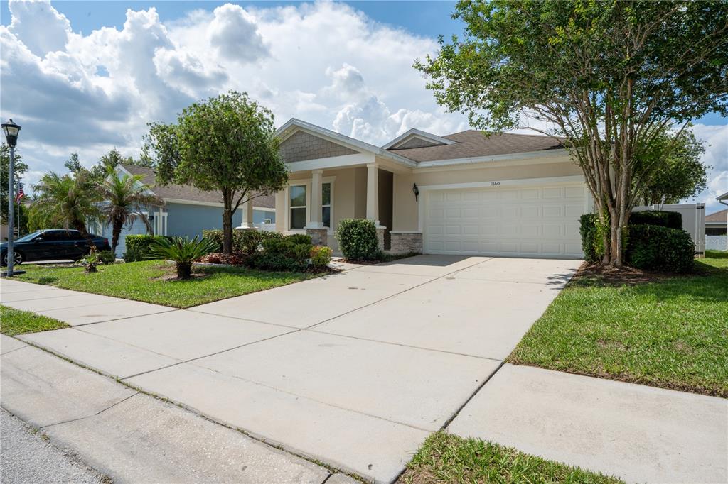 A single-story suburban house with a concrete driveway, a two-car garage, and landscaped front yard — 1860 SKYVIEW DRIVE, AUBURNDALE, FL