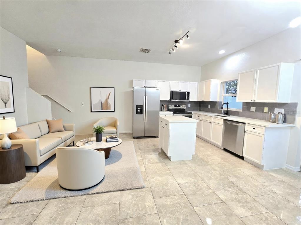 An open-concept kitchen and living area features white cabinetry, stainless steel appliances, and tile flooring — 13241 OPAL COURT, LARGO, FL