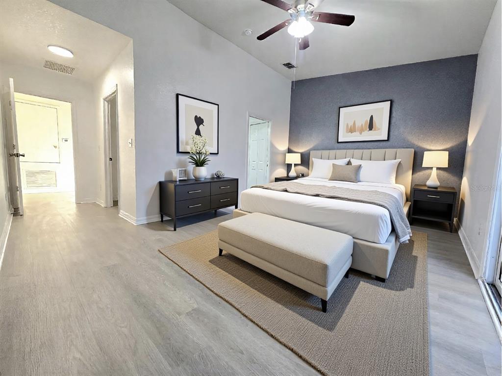 A bedroom features a gray accent wall, a platform bed, and light wood-look flooring — 13241 OPAL COURT, LARGO, FL
