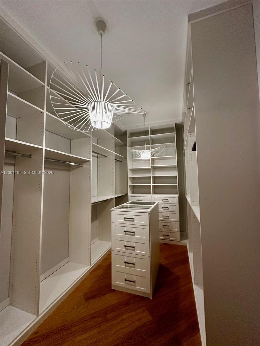 A walk-in closet features white shelving, a central drawer island, and two modern pendant lights — 223 NW 129th Ave # 0, Miami FL 33182, MIAMI, FL