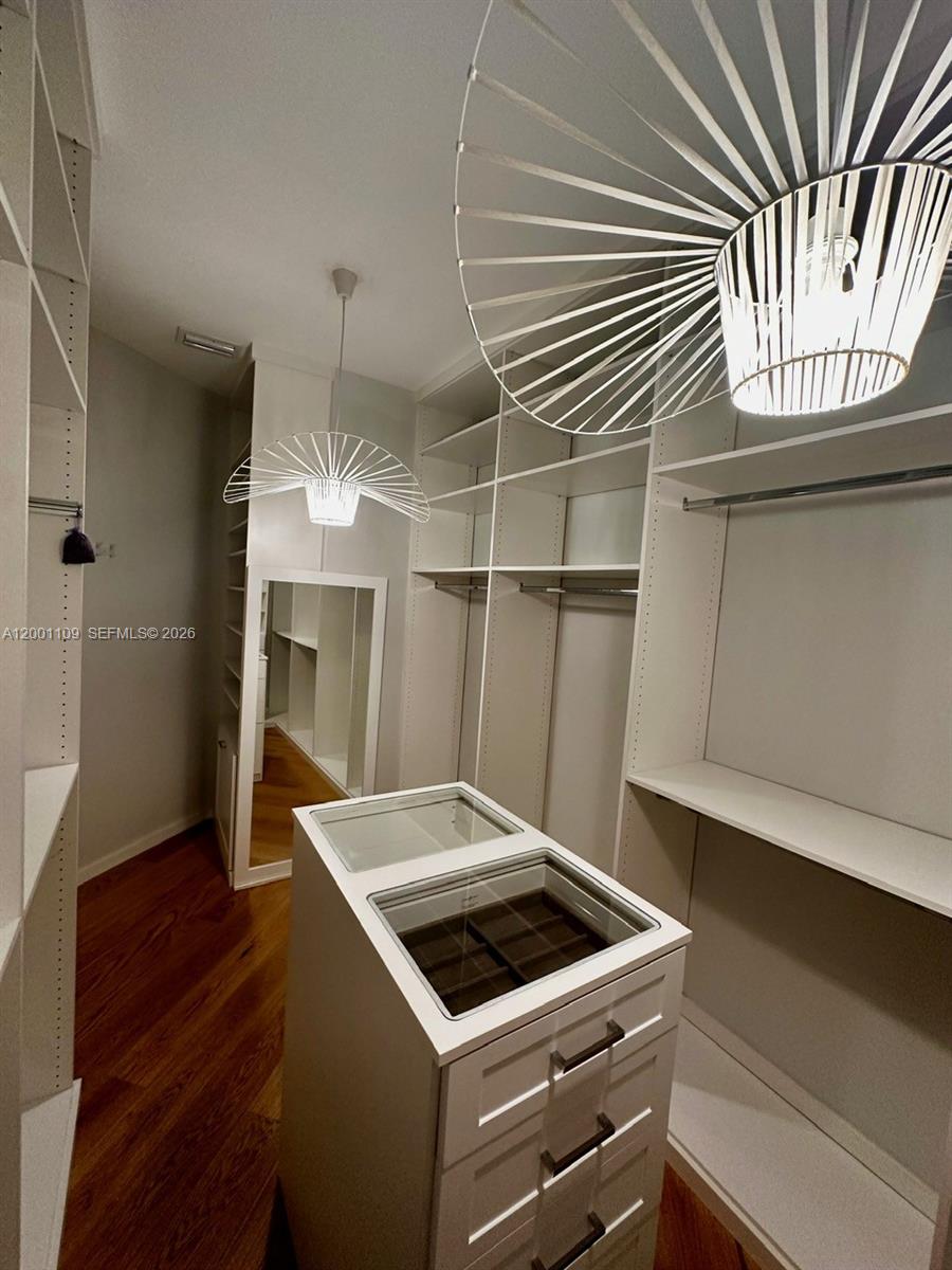 A walk-in closet features white shelving, a central island with drawers, and modern pendant lighting — 223 NW 129th Ave # 0, Miami FL 33182, MIAMI, FL