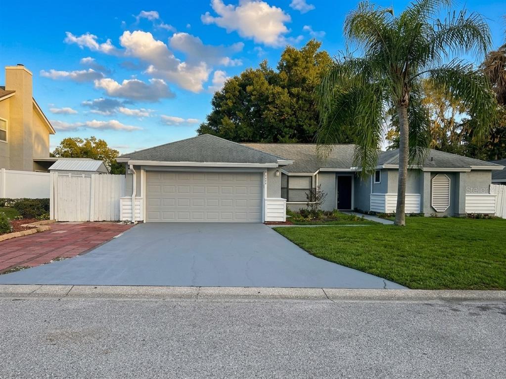 A single-story house with a gray garage, a paved driveway, and a palm tree — 1029 WINDSONG CIRCLE, APOPKA, FL