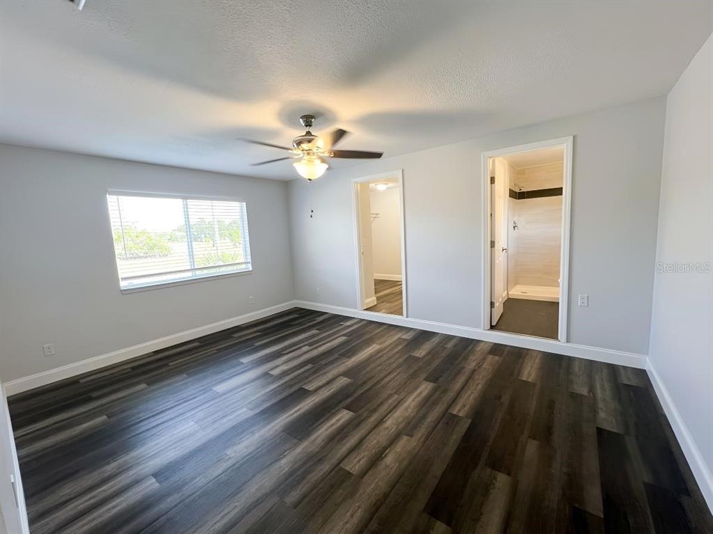 A bedroom with gray walls, dark wood-look flooring, a ceiling fan, and two doorways — 1029 WINDSONG CIRCLE, APOPKA, FL