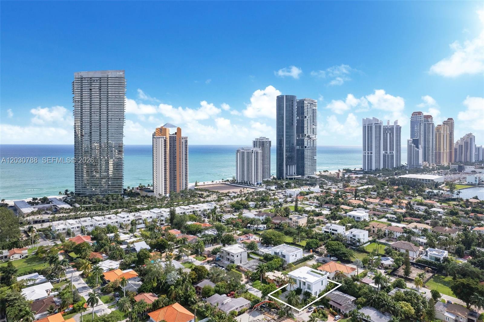 An aerial view shows a white modern house surrounded by trees near a coastal city — 278 190th St, Sunny Isles Beach FL 33160, SUNNY ISLES BEACH, FL