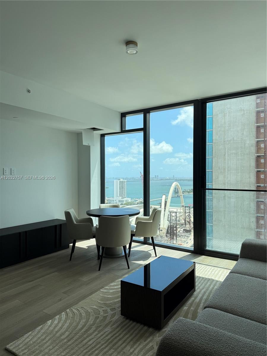 A modern living and dining area features floor-to-ceiling windows with a view of a bridge — 20 NE 11th ST # 3506, Miami FL 331, MIAMI, FL