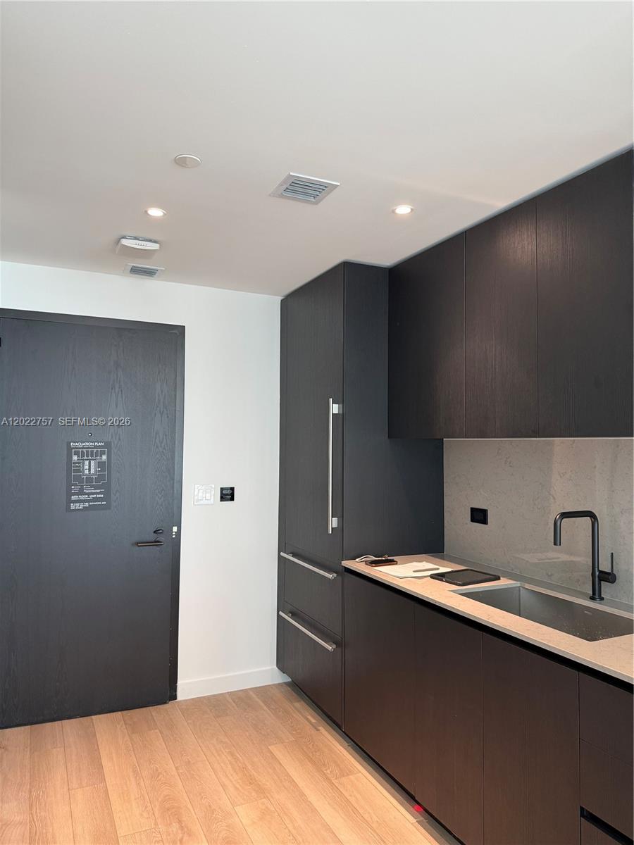 A modern kitchen features dark wood cabinetry, a stone countertop, and a stainless steel sink — 20 NE 11th ST # 3506, Miami FL 331, MIAMI, FL