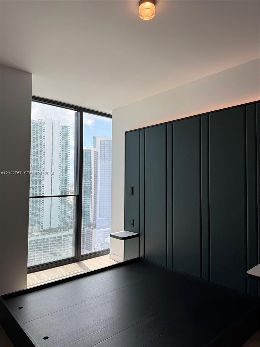 A modern bedroom features a dark paneled accent wall, a platform bed, and floor-to-ceiling windows — 20 NE 11th ST # 3506, Miami FL 331, MIAMI, FL