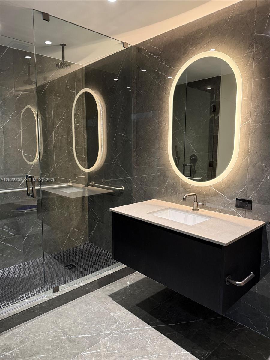 A modern bathroom features a floating vanity, a backlit oval mirror, and dark marble tiling — 20 NE 11th ST # 3506, Miami FL 331, MIAMI, FL
