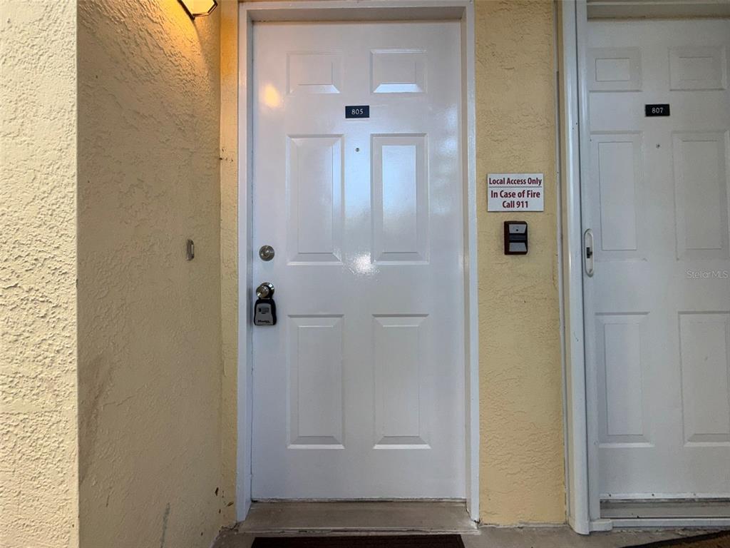 A white apartment door labeled 805 with a lockbox sits next to door 807 — 3001 58TH AVENUE S UNIT 805, ST PETERSBURG, FL