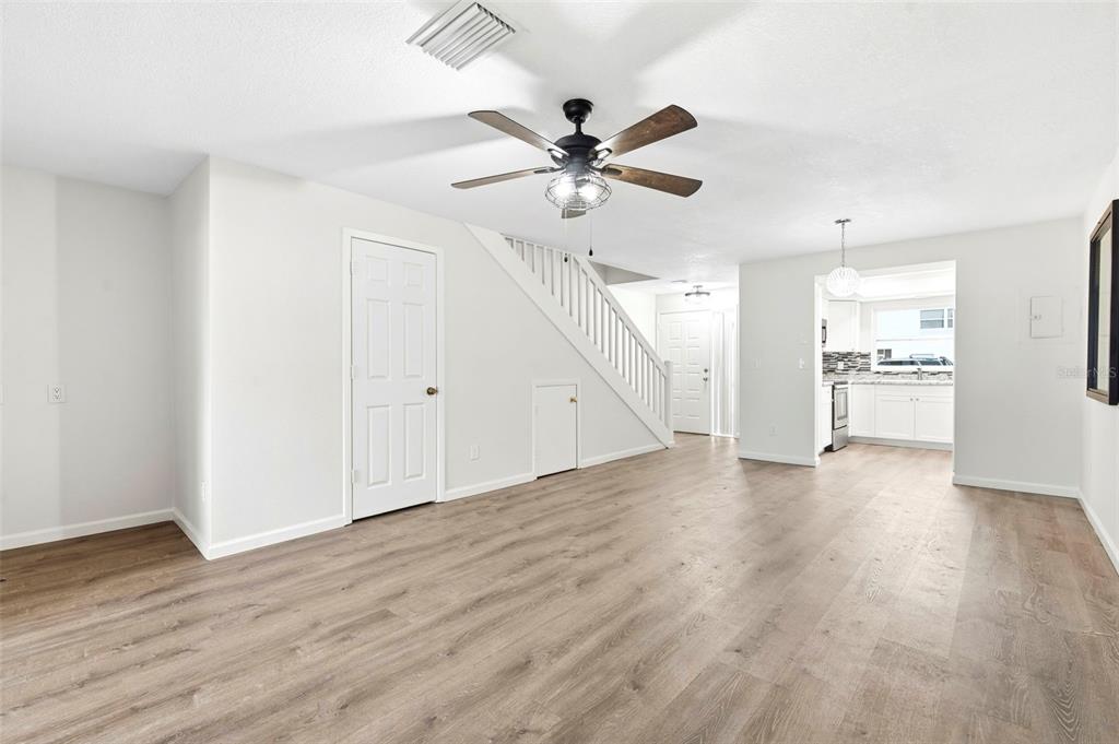 An open living area features light wood-look flooring, a ceiling fan, and a staircase — 2871 S PINES DRIVE UNIT 31, LARGO, FL