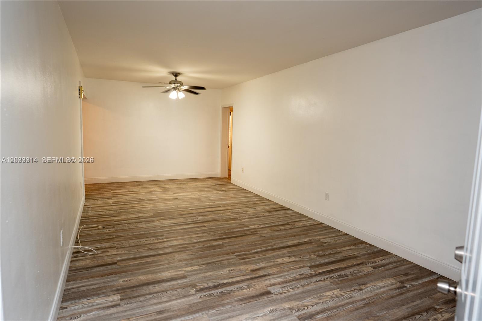 An empty room features white walls, a ceiling fan, and wood-look laminate flooring — 259 NE 56th St, Miami FL 33137, MIAMI, FL