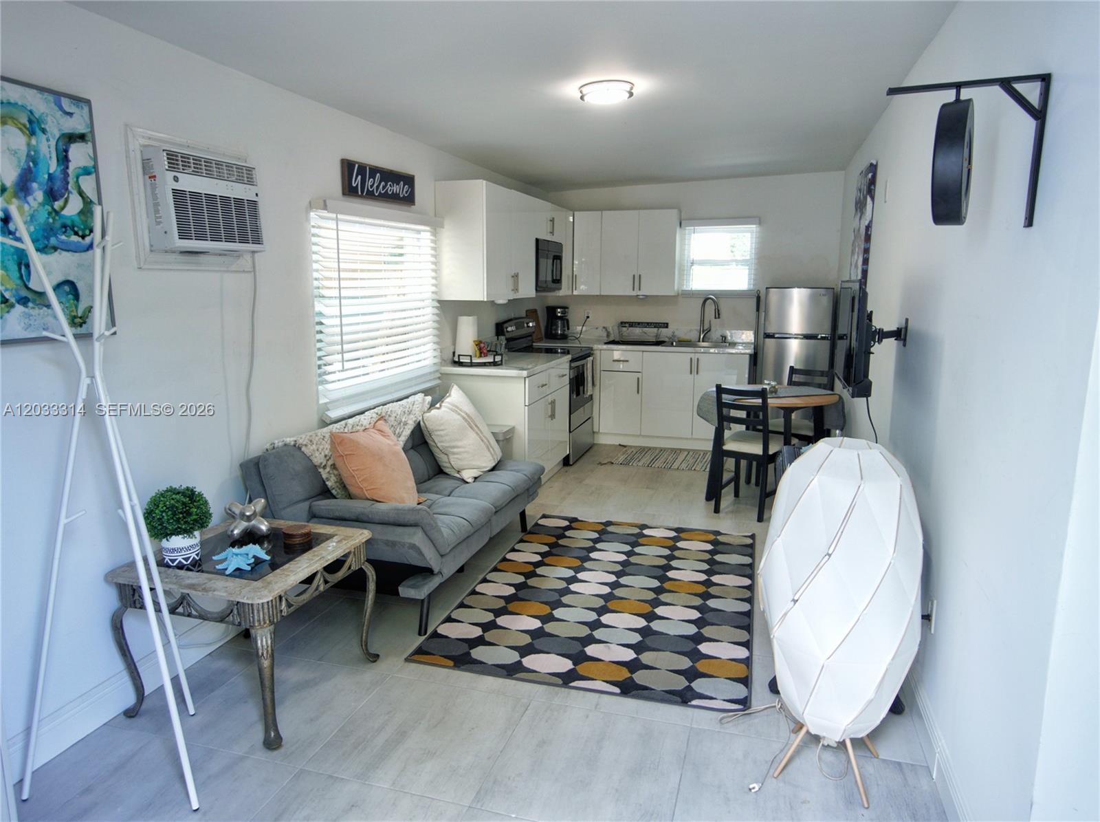 A small studio apartment features a kitchenette, a gray sofa, and a patterned area rug — 259 NE 56th St, Miami FL 33137, MIAMI, FL