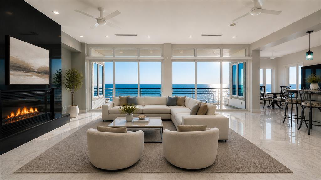 A living room with a fireplace, large sectional sofa, and floor-to-ceiling windows overlooking the ocean — 9200 BLIND PASS ROAD, SARASOTA, FL