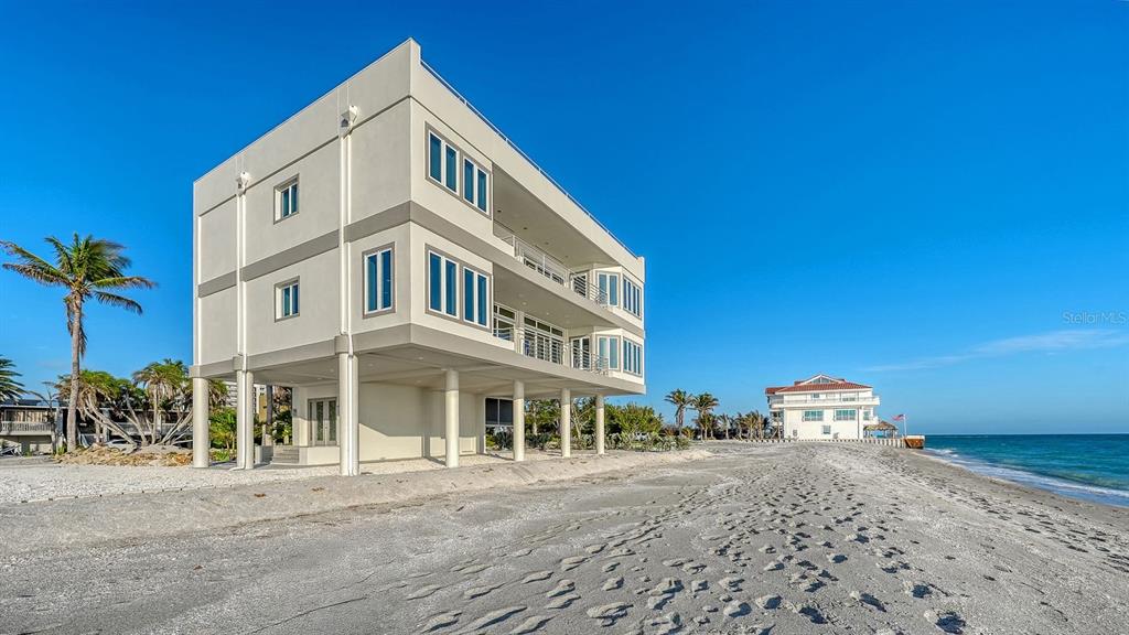 A modern, elevated multi-story house stands on a sandy beach next to the ocean — 9200 BLIND PASS ROAD, SARASOTA, FL