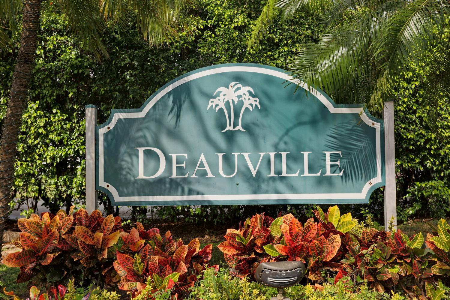 A teal sign with the word Deauville and a palm tree icon stands among tropical plants — 6550 S Oriole Boulevard # 2050, Delray Beach FL 33446, DELRAY BEACH, FL