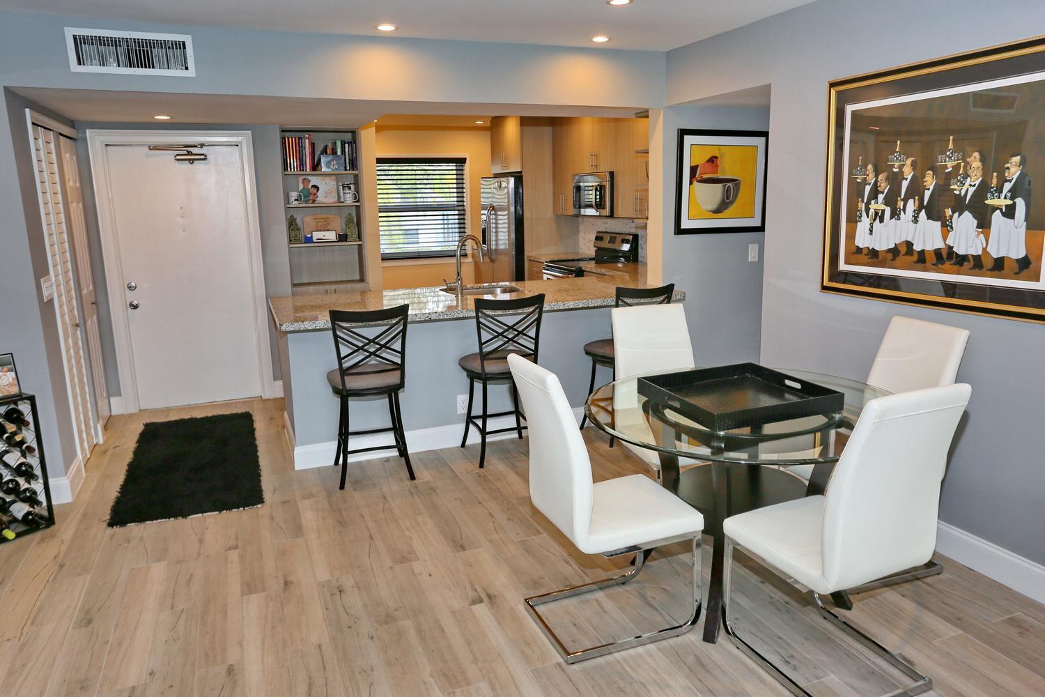 A kitchen with a breakfast bar and dining area featuring white chairs and light flooring — 6550 S Oriole Boulevard # 2050, Delray Beach FL 33446, DELRAY BEACH, FL