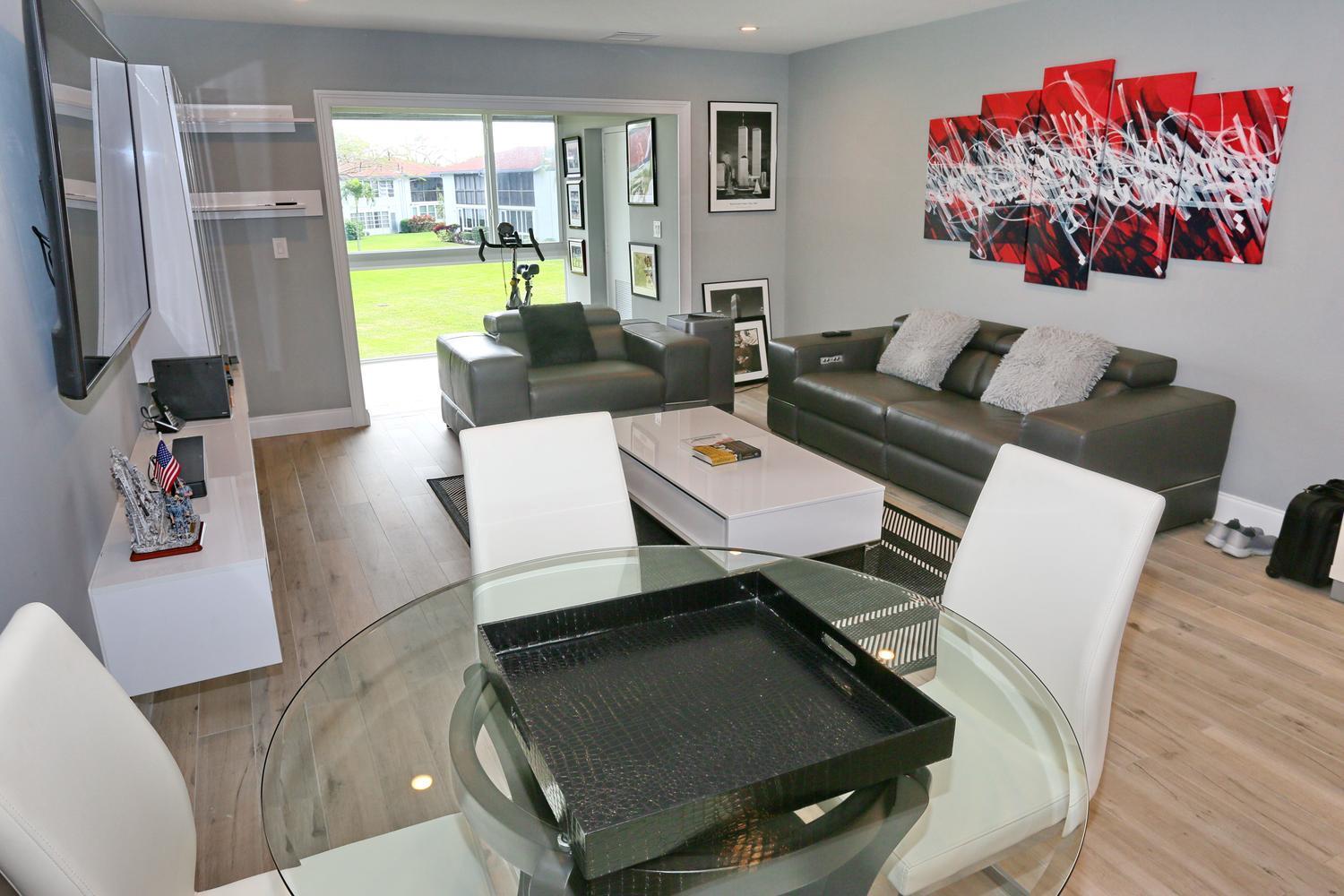 A living and dining area features gray walls, wood-look flooring, a glass table, and furniture — 6550 S Oriole Boulevard # 2050, Delray Beach FL 33446, DELRAY BEACH, FL