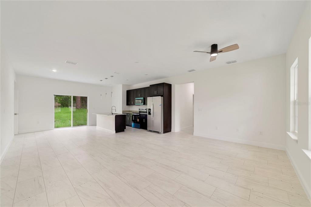 An open-concept kitchen and living area features dark cabinets, stainless steel appliances, and tile flooring — 3355 W MARIE DRIVE, CITRUS SPRINGS, FL