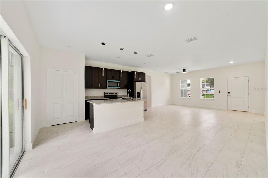 A kitchen with dark cabinets and a white island opens into a spacious living area — 3355 W MARIE DRIVE, CITRUS SPRINGS, FL