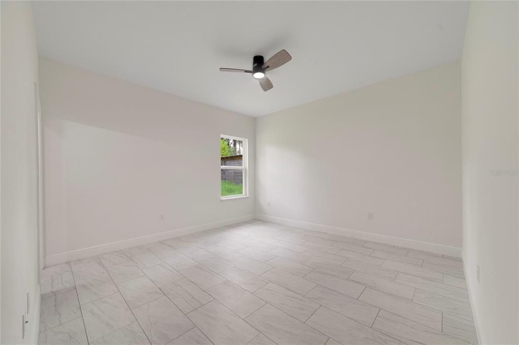 A bright bedroom features white walls, light-colored tile flooring, and a ceiling fan — 3355 W MARIE DRIVE, CITRUS SPRINGS, FL