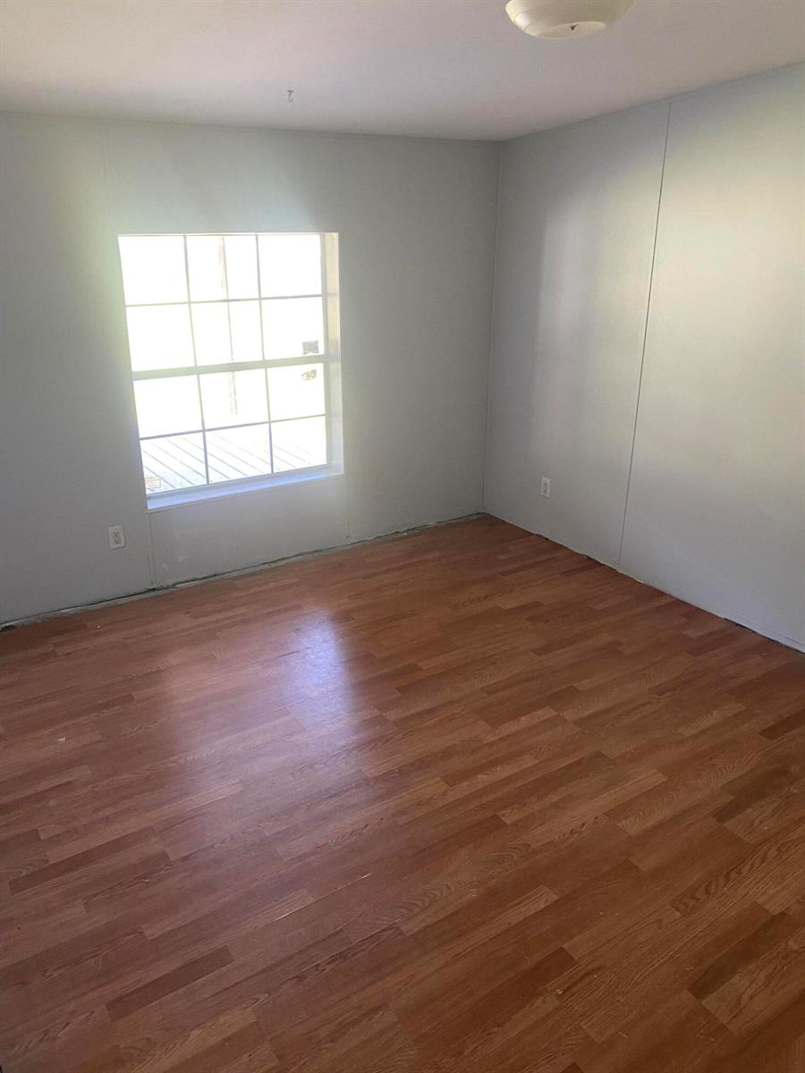 An empty room with light gray walls, wood-look flooring, and a single window — 170 S Lindero Street, Clewiston FL 33440, CLEWISTON, FL
