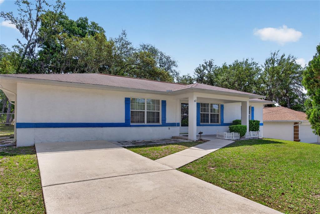 A single-story house with white stucco walls, blue trim, and a concrete driveway — 42 LARCH RADIAL, OCALA, FL