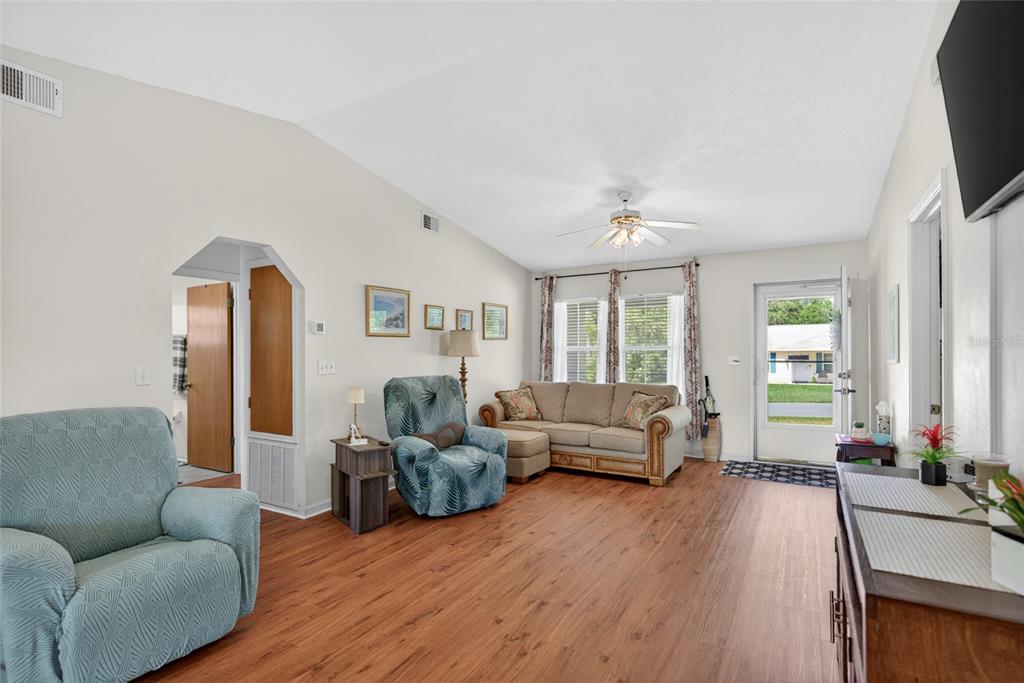 A living room features light walls, wood-look flooring, a vaulted ceiling, and a glass-paneled door — 42 LARCH RADIAL, OCALA, FL