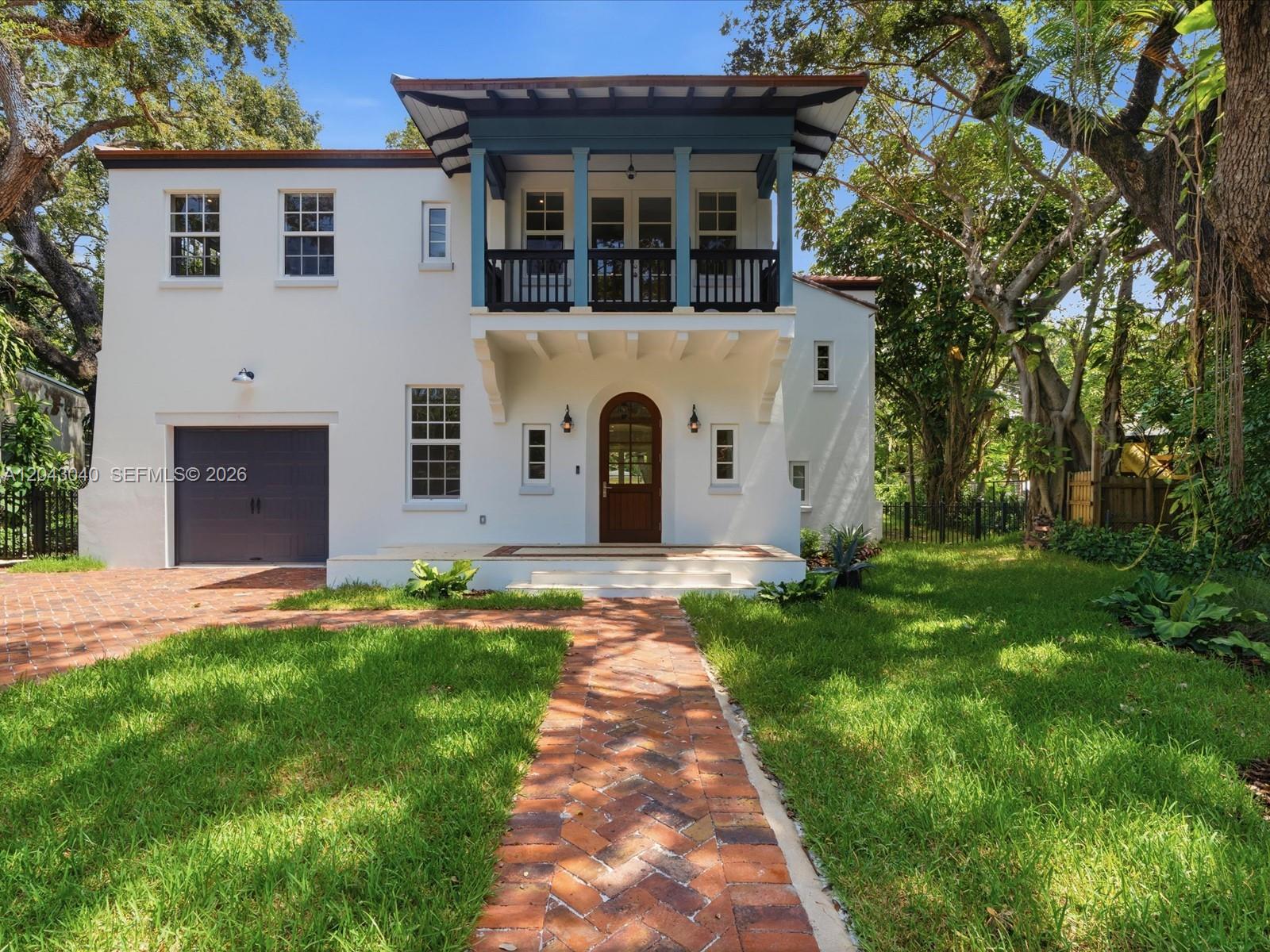 A three-story white stucco house features a blue-trimmed balcony, arched front door, and brick walkway — 6333 SW 69th St, South Miami FL 33143, SOUTH MIAMI, FL