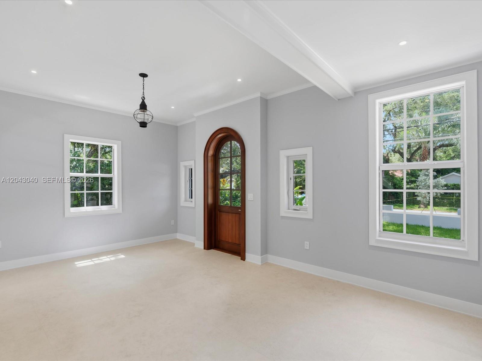 A bright room features light gray walls, a wooden arched door, and multiple windows — 6333 SW 69th St, South Miami FL 33143, SOUTH MIAMI, FL
