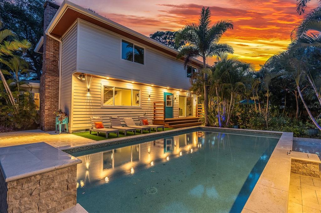 A two-story house with light siding, a brick chimney, and a swimming pool at sunset — 6921 MANGO AVENUE S, ST PETERSBURG, FL