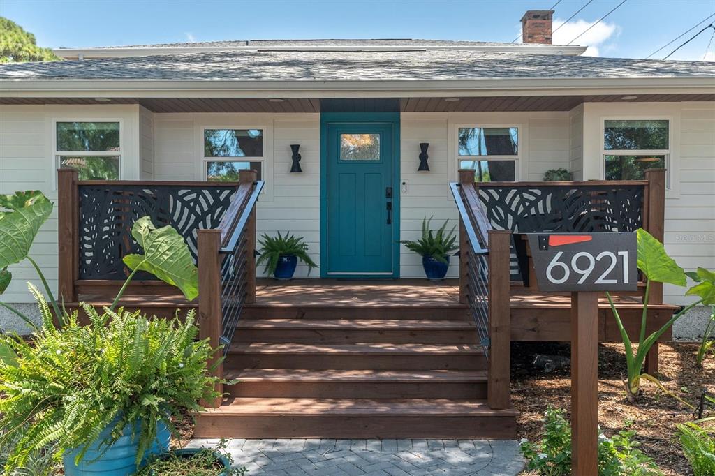 A front porch with wooden steps, decorative metal railings, and a teal front door — 6921 MANGO AVENUE S, ST PETERSBURG, FL