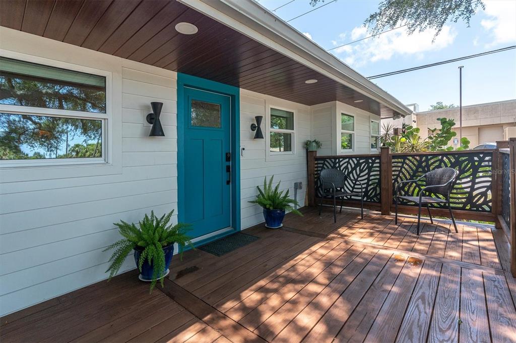 A wooden deck leads to a bright blue front door on a white house exterior — 6921 MANGO AVENUE S, ST PETERSBURG, FL