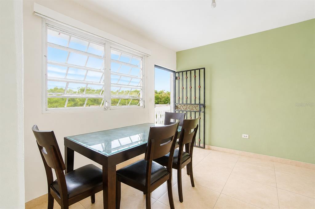 A dining room with a glass-topped table, four chairs, a large window, and green wall — Calle C URB LOS CHOFERES CALLE C UNIT 28, SAN JUAN, PR