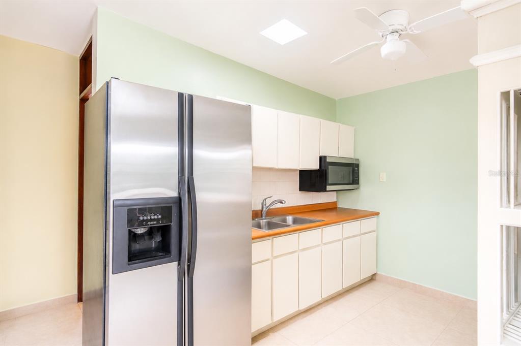 A kitchen features a stainless steel refrigerator, white cabinets, a wood countertop, and light green walls — Calle C URB LOS CHOFERES CALLE C UNIT 28, SAN JUAN, PR