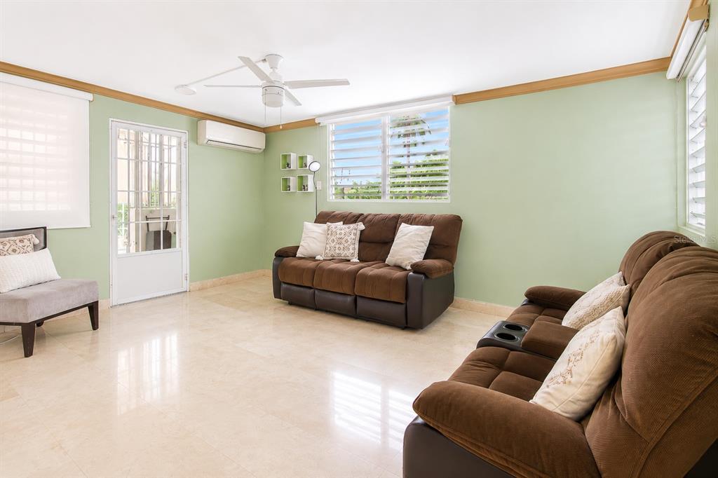 A living room with light green walls, tile flooring, two brown sofas, and a ceiling fan — Calle C URB LOS CHOFERES CALLE C UNIT 28, SAN JUAN, PR
