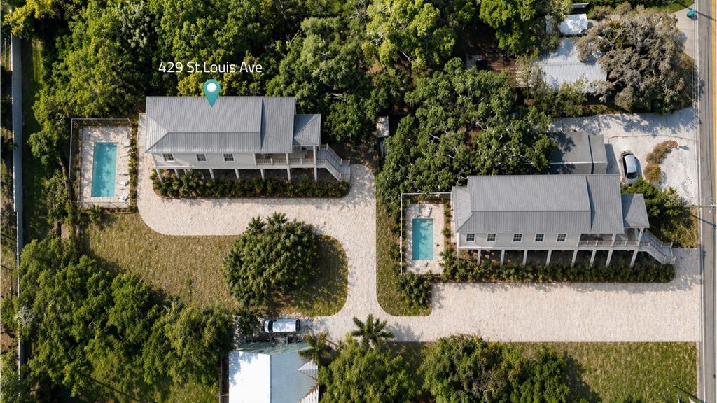 An aerial view shows two elevated houses with metal roofs, private pools, and gravel driveways — 429 ST LOUIS AVENUE, PALM HARBOR, FL
