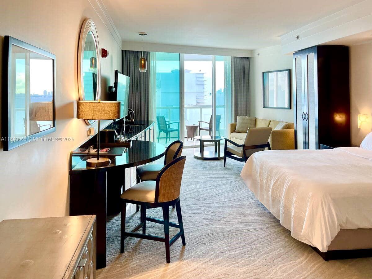 A hotel room features a bed, a desk with chairs, and a balcony with seating — 4391 Collins Ave # 918, Miami Beach FL 33140, MIAMI BEACH, FL