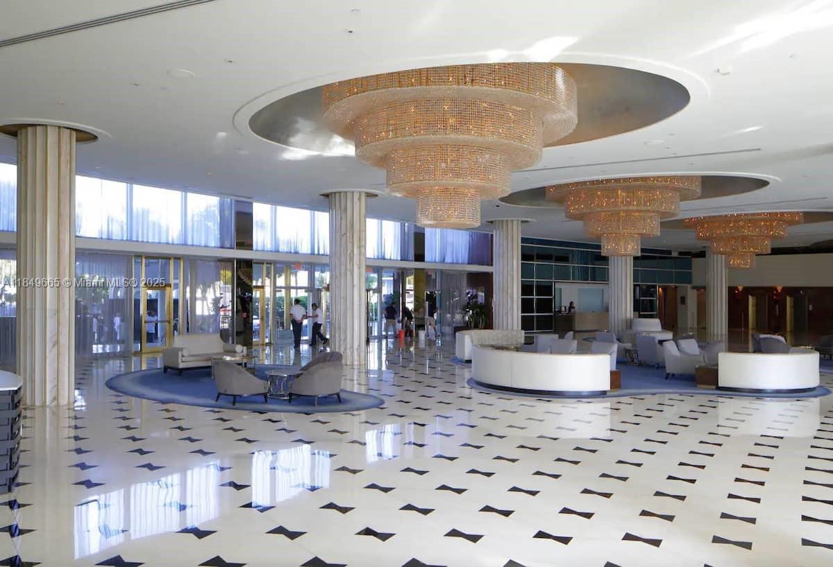 A spacious lobby features white marble floors, multiple crystal chandeliers, and curved seating areas — 4391 Collins Ave # 918, Miami Beach FL 33140, MIAMI BEACH, FL