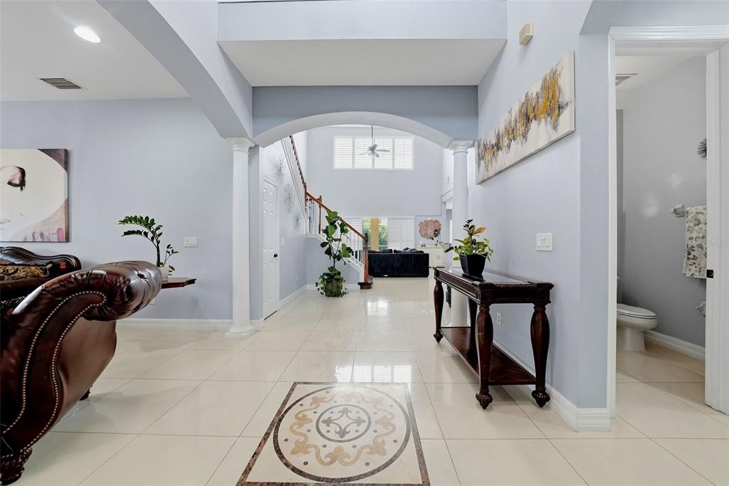 A bright foyer features light tile floors, an arched entryway, and a staircase in back — 18043 COZUMEL ISLE DRIVE, TAMPA, FL