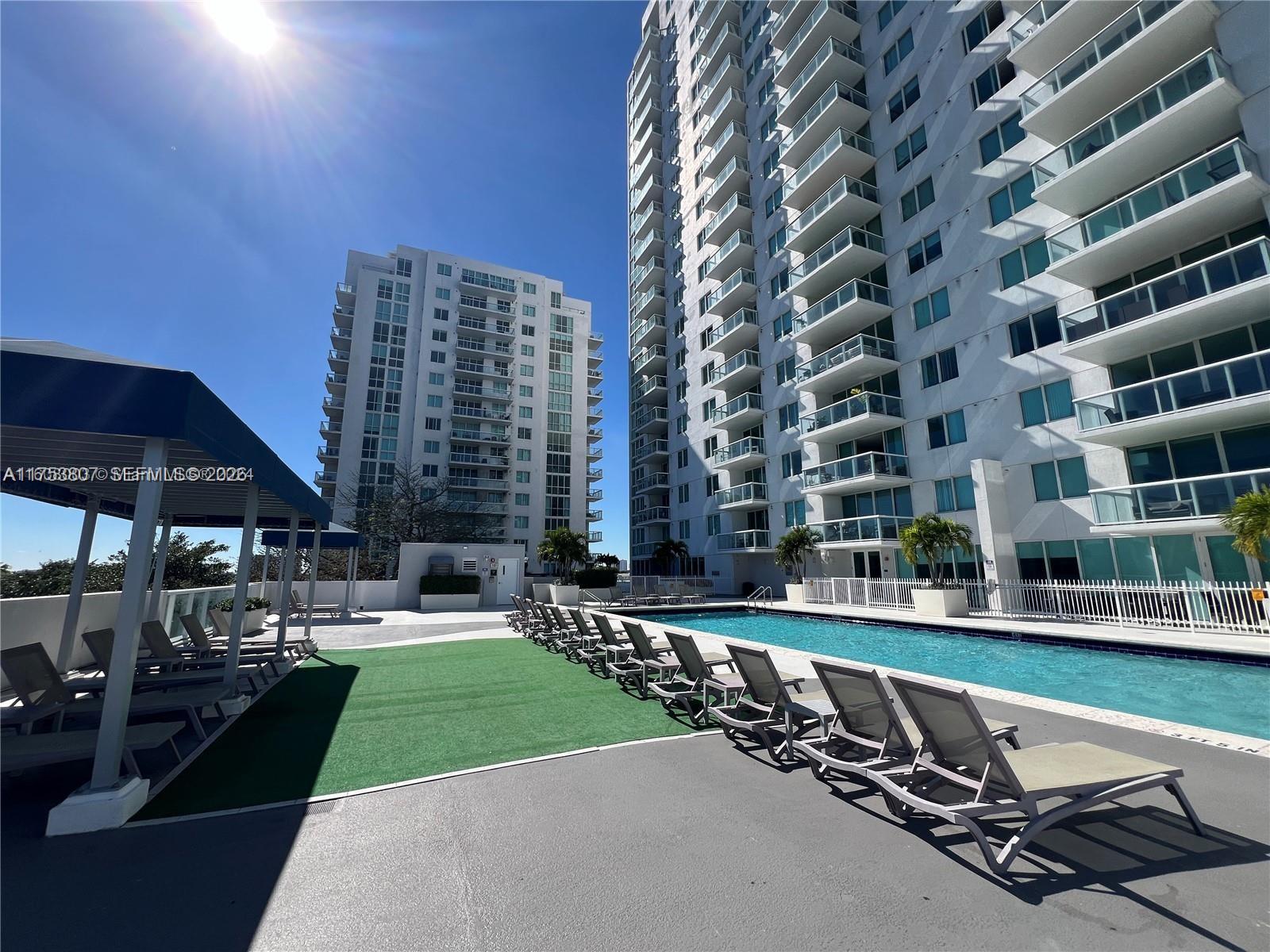 A swimming pool area features lounge chairs on a deck next to two high-rise buildings — 1861 NW S River Dr # 1504, Miami FL 33125, MIAMI, FL