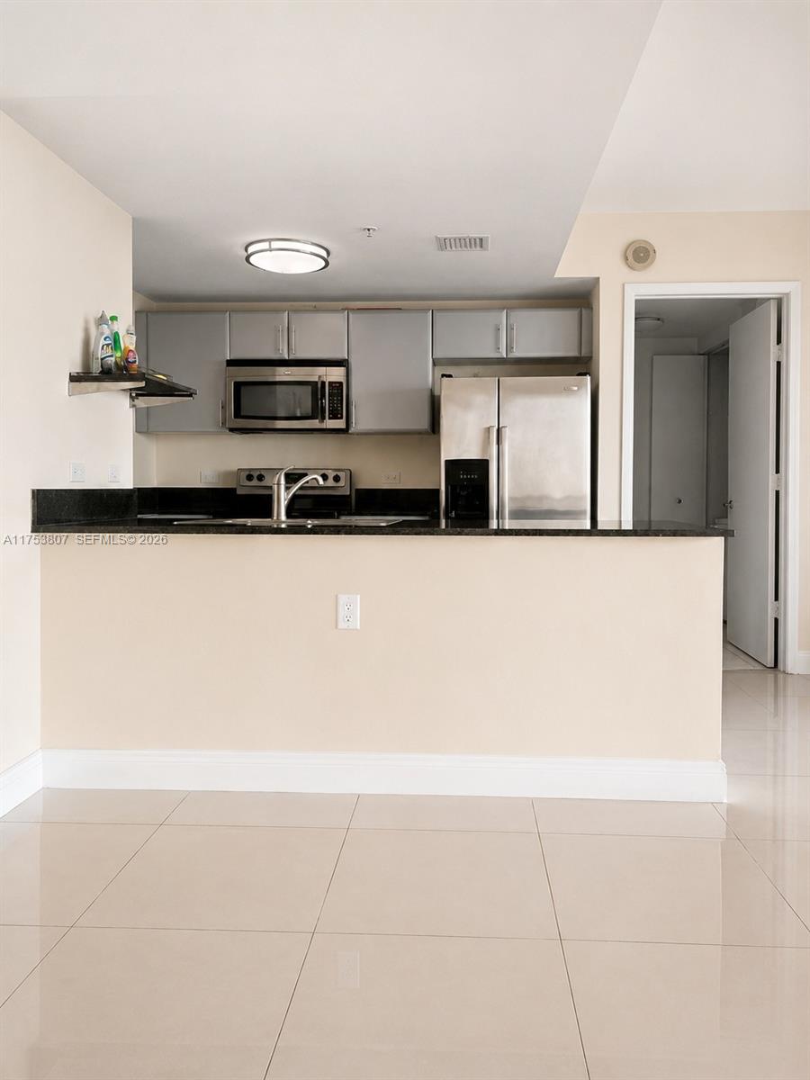 A kitchen features stainless steel appliances, dark countertops, and light-colored tile flooring — 1861 NW S River Dr # 1504, Miami FL 33125, MIAMI, FL