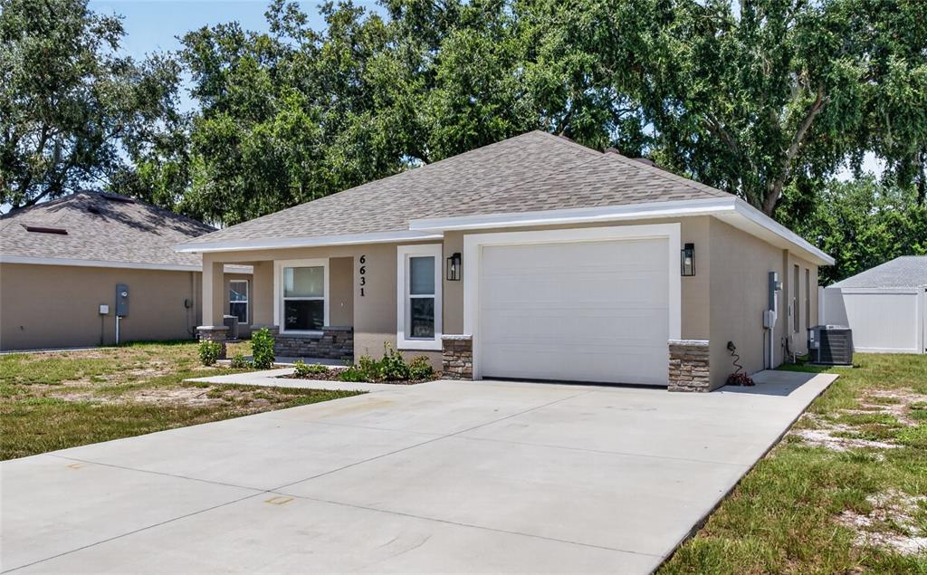A single-story house with a beige stucco exterior, stone accents, and a concrete driveway — 6631 THORNHILL ROAD, WINTER HAVEN, FL