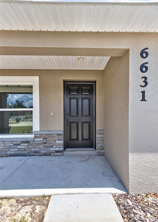 The exterior view shows a front porch with a black door and stone accents — 6631 THORNHILL ROAD, WINTER HAVEN, FL