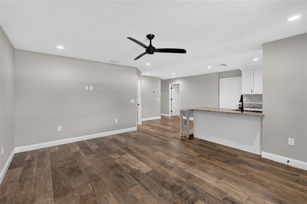 An open-concept living area features wood-look flooring, a ceiling fan, and a kitchen breakfast bar — 6631 THORNHILL ROAD, WINTER HAVEN, FL