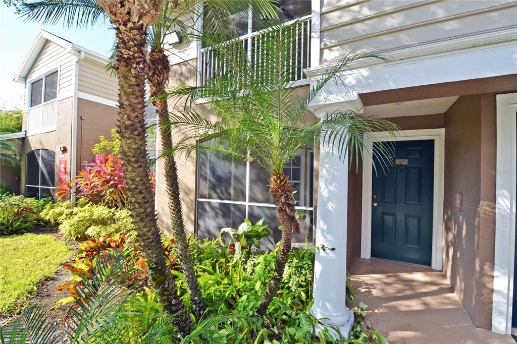 A dark blue front door is set under a covered entryway with a white column — 7428 VISTA WAY UNIT 104, BRADENTON, FL