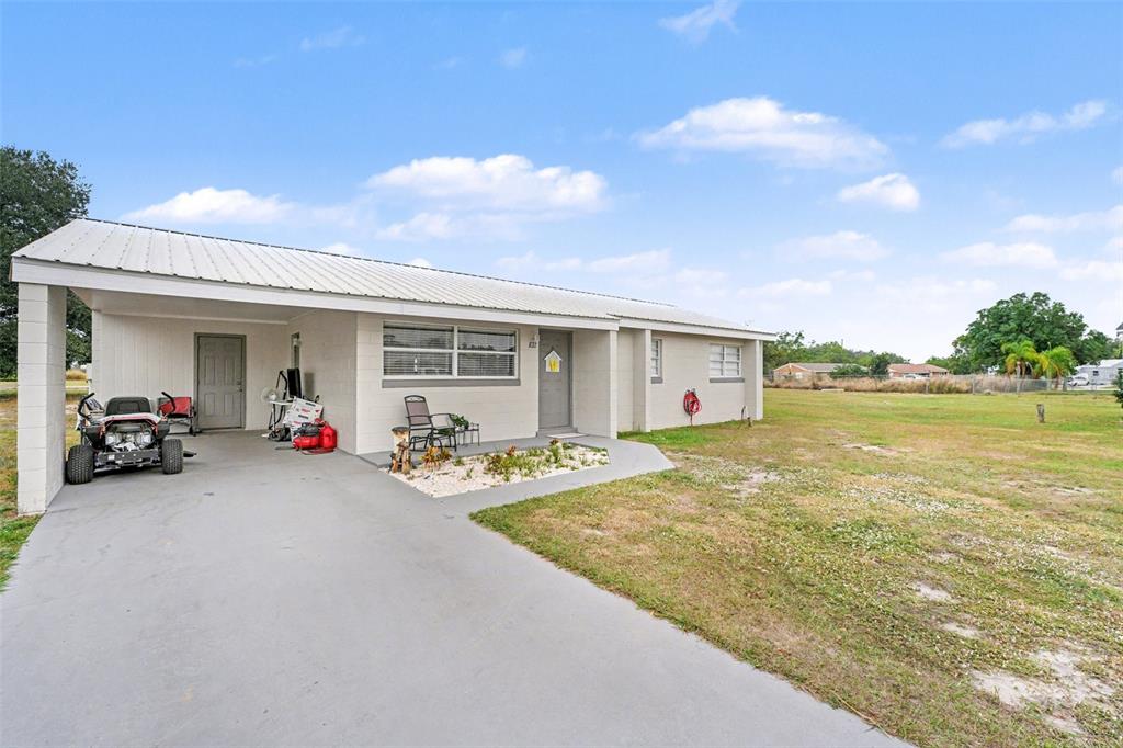 A single-story house with a metal roof, a carport, and a concrete driveway — 45 QUEENS COURT, FROSTPROOF, FL